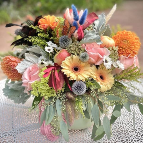 Colorful mixed bouquet with roses, gerbera daisies, and orange blooms in a vase