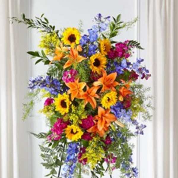 Tall standing floral spray with sunflowers, lilies, and blue flowers