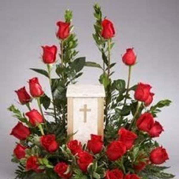 Red roses arranged around a white memorial lantern with a cross