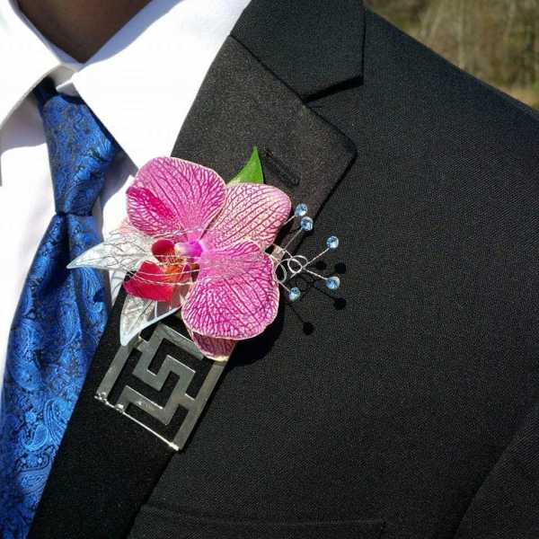 Pink orchid boutonniere pinned to a black suit jacket