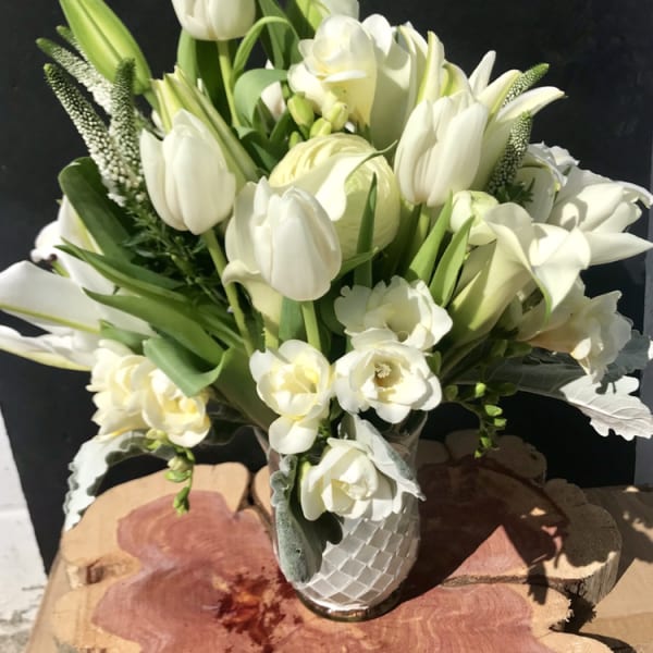 White tulips and lilies arranged in a textured white vase
