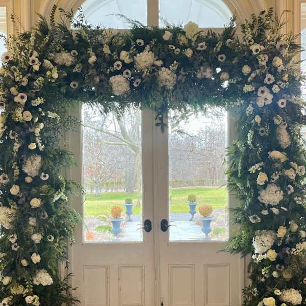 Large floral arch of white blooms framing double doors