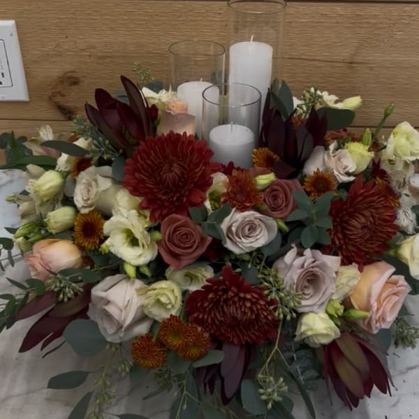 Low floral centerpiece with candles in glass cylinders