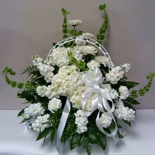 White floral sympathy arrangement with a satin ribbon and arch handle