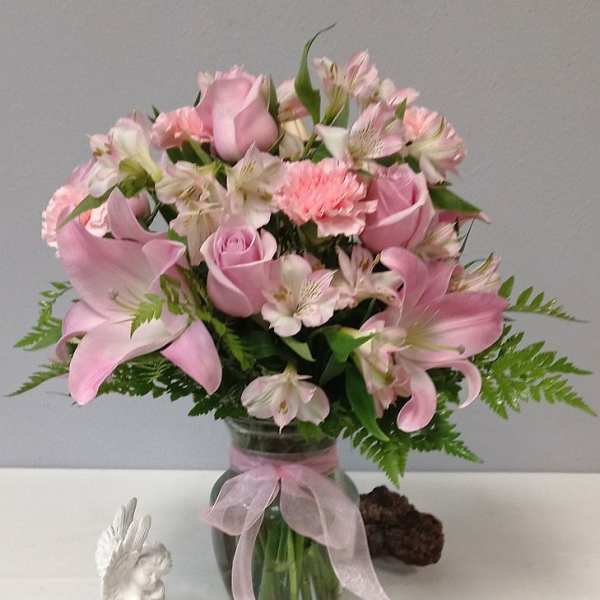 Pink lilies and roses in a glass vase with a ribbon