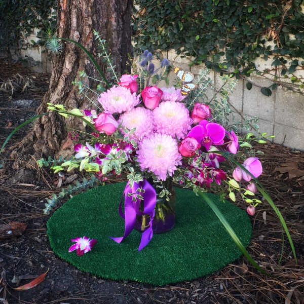 Pink floral arrangement with roses and orchids in a glass vase