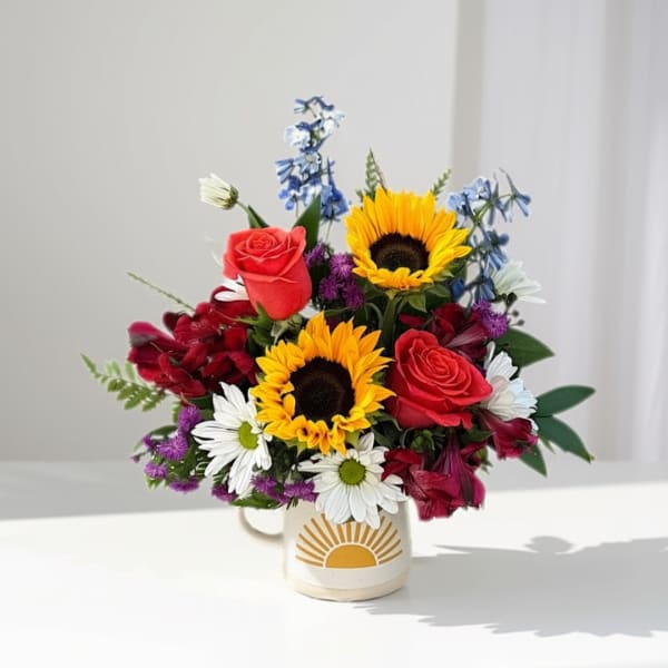 Bouquet of sunflowers, red roses, and daisies in a mug vase