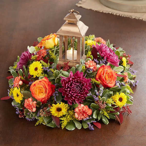 Round floral centerpiece with a lantern candle in the middle