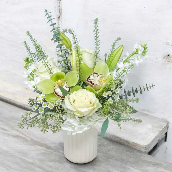White and green floral arrangement in a white vase