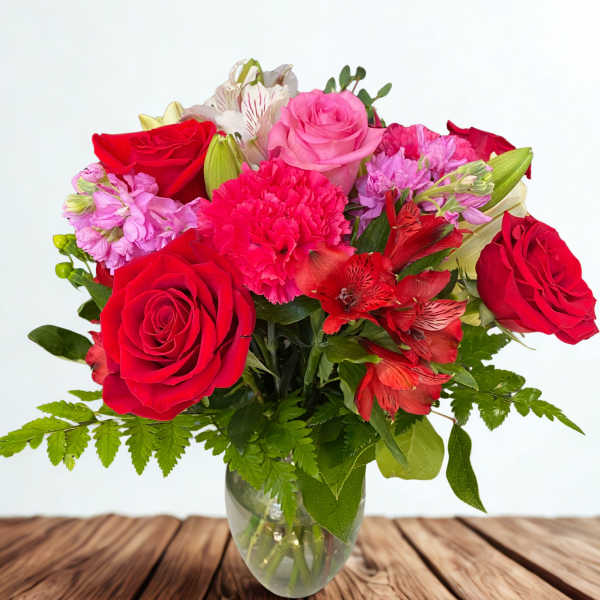 Bouquet of red and pink roses with carnations in a glass vase