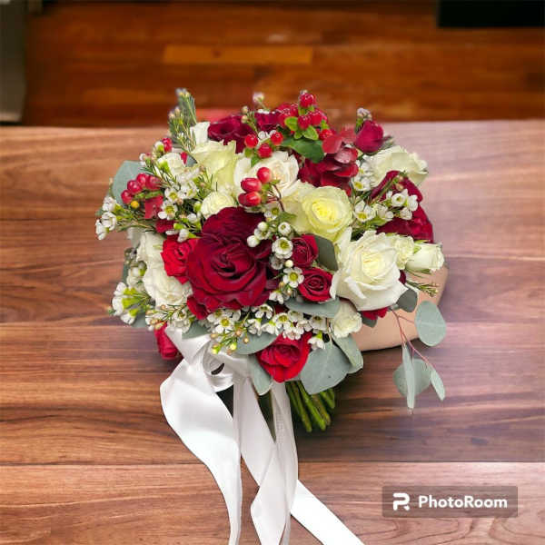 Bouquet of red and white roses with small white filler flowers and a white ribbon