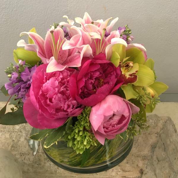 Pink lilies and peonies arranged in a glass bowl vase