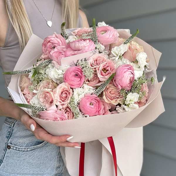 Pink and white bouquet of roses and ranunculus wrapped in pale paper