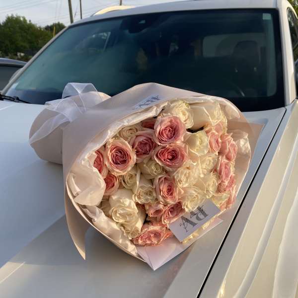 Bouquet of pink and cream roses wrapped in pale paper