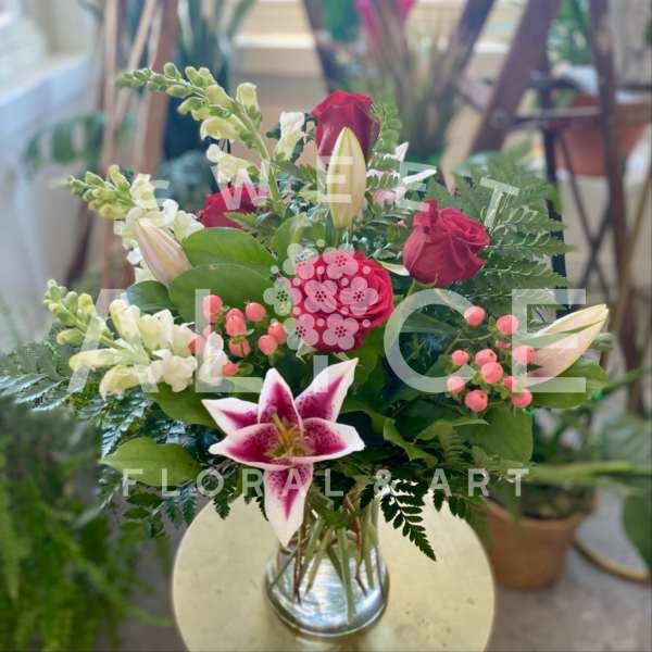 Bouquet of red roses and pink lilies in a clear glass vase