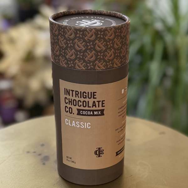 Cylindrical cocoa mix container with brown label on a table