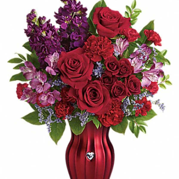 Red roses and purple flowers arranged in a red vase