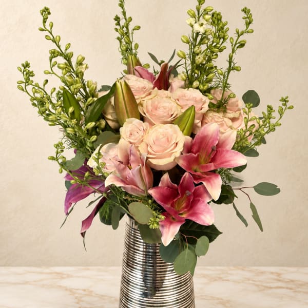 Pink roses and lilies in a silver striped vase