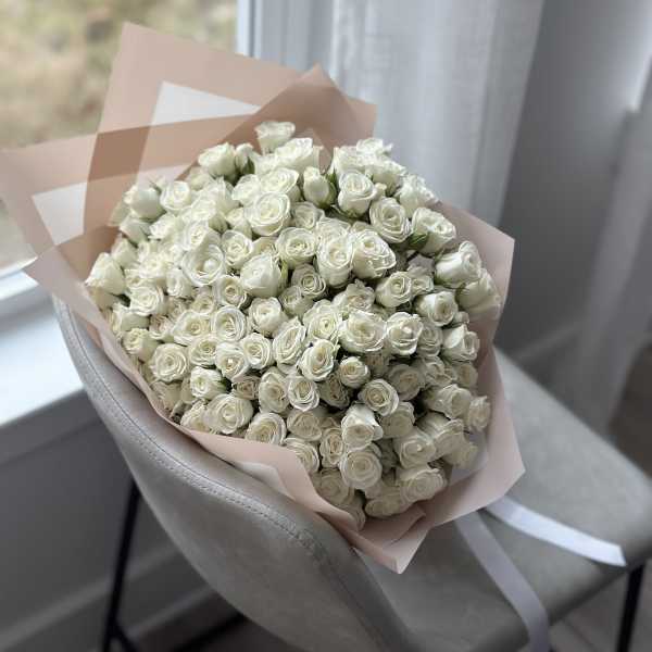 Large bouquet of white roses wrapped in pale pink paper