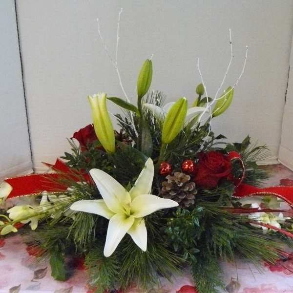 Low floral centerpiece with white lilies, red roses, and red ribbon