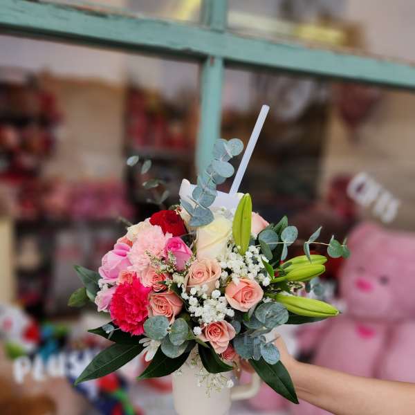 Mixed bouquet of pink and white flowers in a white mug vase