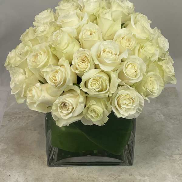 Cream rose bouquet in a square glass vase