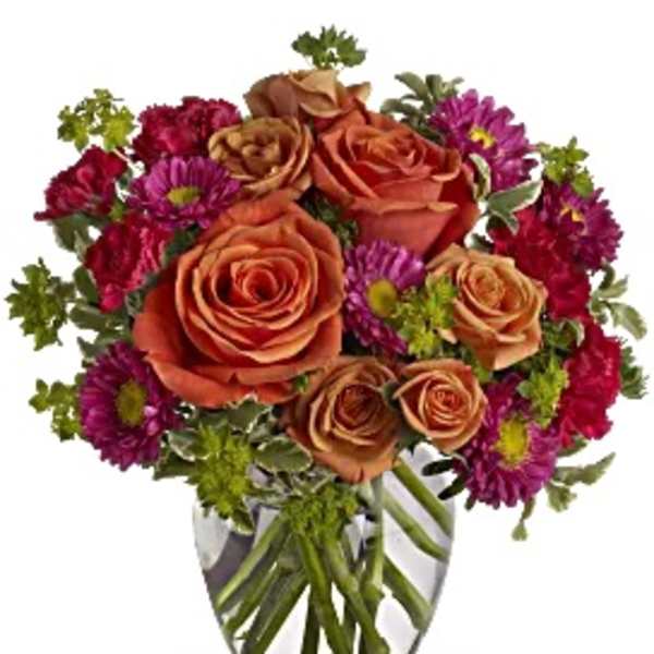 Bouquet of orange roses and purple daisies in a clear glass vase