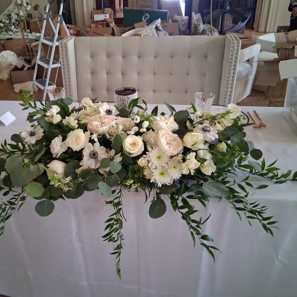 White floral centerpiece with roses and anemones on a table