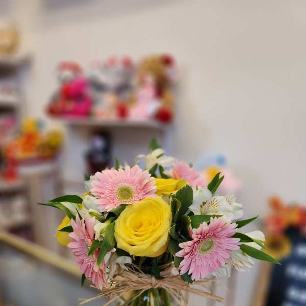 Bouquet of yellow roses and pink gerbera daisies in a glass vase