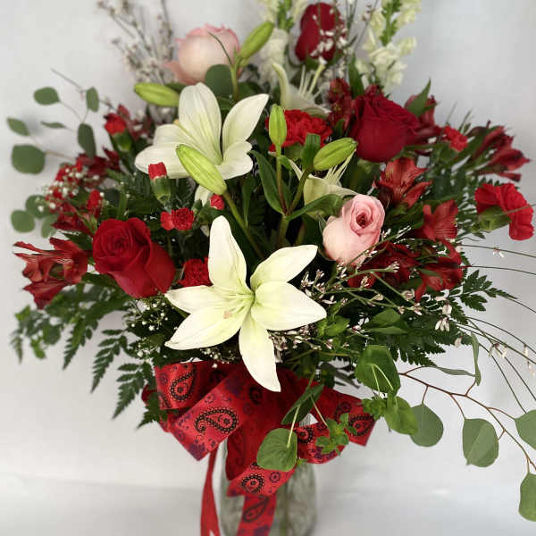 Bouquet of red and white flowers in a glass vase with a red ribbon