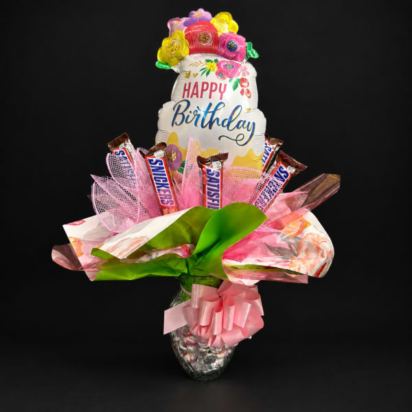 Birthday balloon bouquet with candy bars in a glass vase
