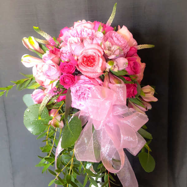 Pink rose bouquet with a large pink ribbon and trailing greenery