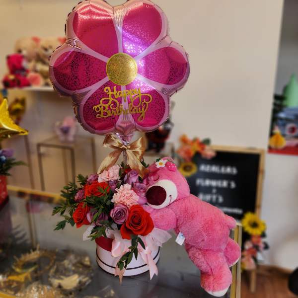 Pink birthday balloon with roses and a teddy bear in a gift box