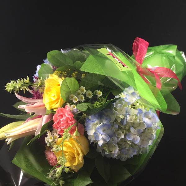 Wrapped bouquet of yellow roses, blue hydrangea, and pink lilies