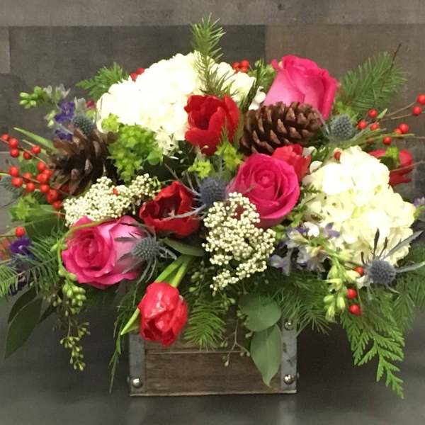 Mixed bouquet with pink and red roses, white blooms, and pinecones in a wooden box