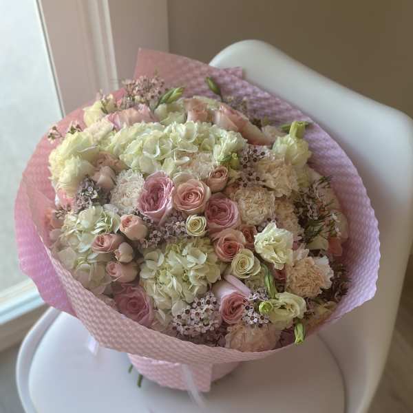 Pink and cream bouquet of roses and hydrangeas wrapped in pink paper