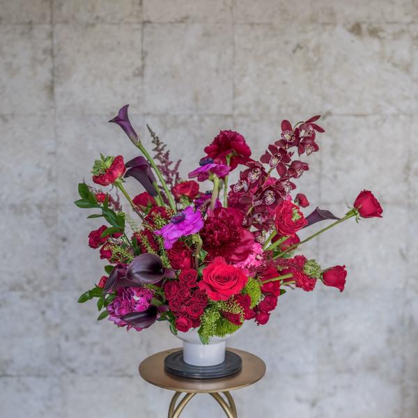 Bright pink and purple floral arrangement in a white vase