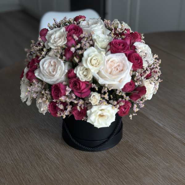 Bouquet of white and magenta roses in a black hat box