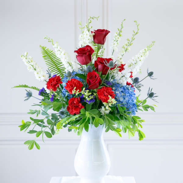 Red roses and blue hydrangeas in a white vase