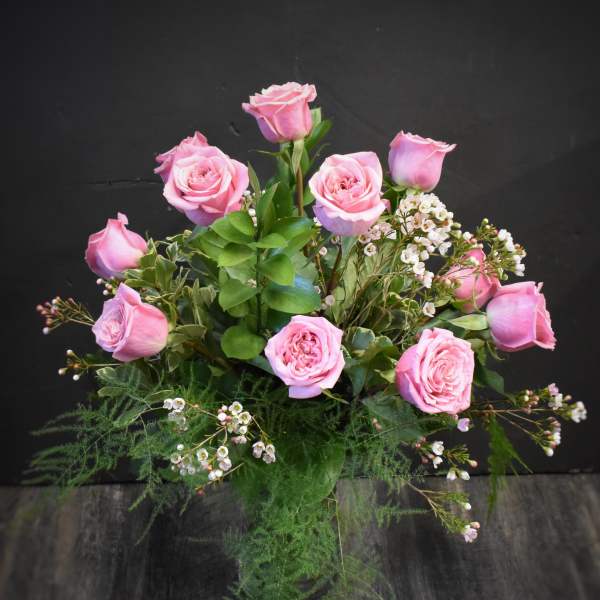 Arrangement of pink roses with small white blossoms in a clear glass vase