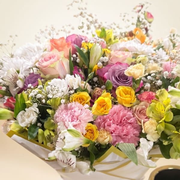 Mixed bouquet of roses, carnations, and lilies in white wrap