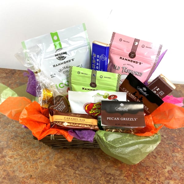 Basket of assorted candy and snack packages with colorful tissue paper