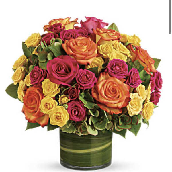 Bouquet of orange, pink, and yellow roses in a green glass vase