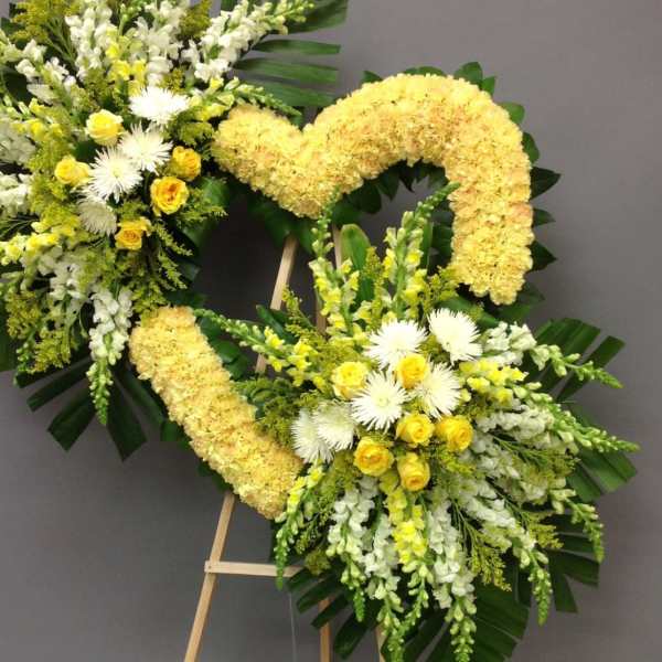 Two yellow and white floral wreaths on easels against a gray wall