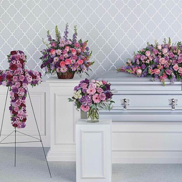 Funeral casket surrounded by pink and purple floral sprays
