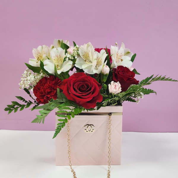 Red roses and white lilies in a pink gift box with a gold chain