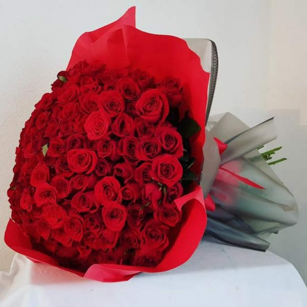 Large bouquet of red roses wrapped in red and gray paper