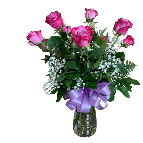 Medium vase arrangement of pink roses with white filler flowers and a lavender ribbon bow