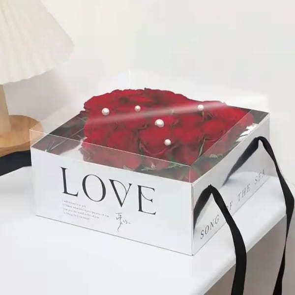 Box of red roses with clear lid and black ribbon handles