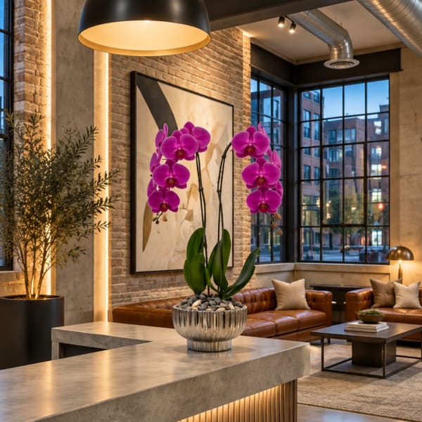 Potted purple orchids in a silver planter on a table